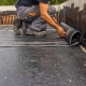 Worker laying the vapor barrier for the roof, bituminous membrane to be welded with flame