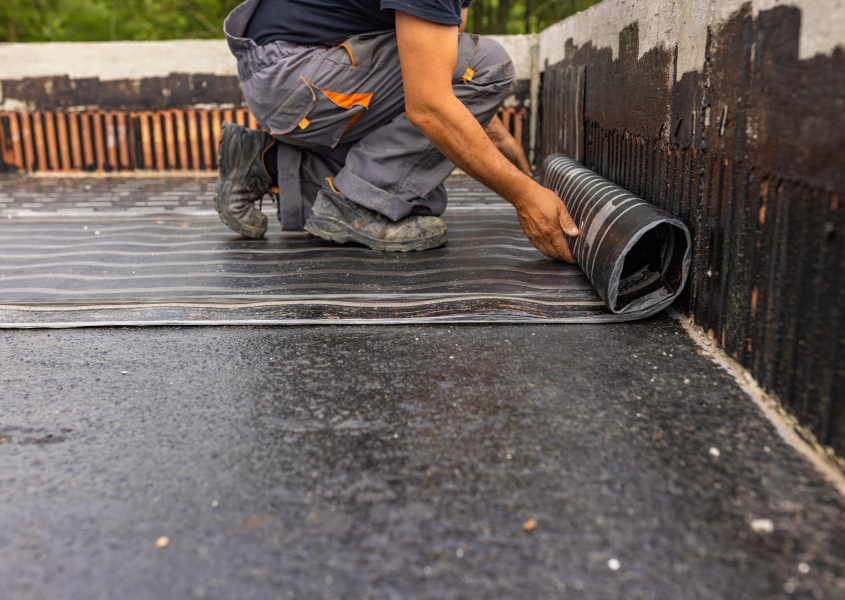 Worker laying the vapor barrier for the roof, bituminous membrane to be welded with flame