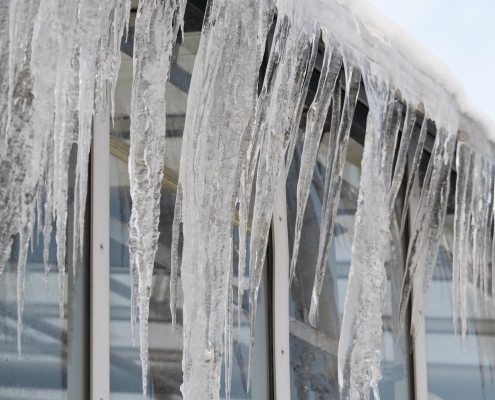 Icicles hang from roof and wall in winter frozen