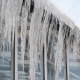 Icicles hang from roof and wall in winter frozen