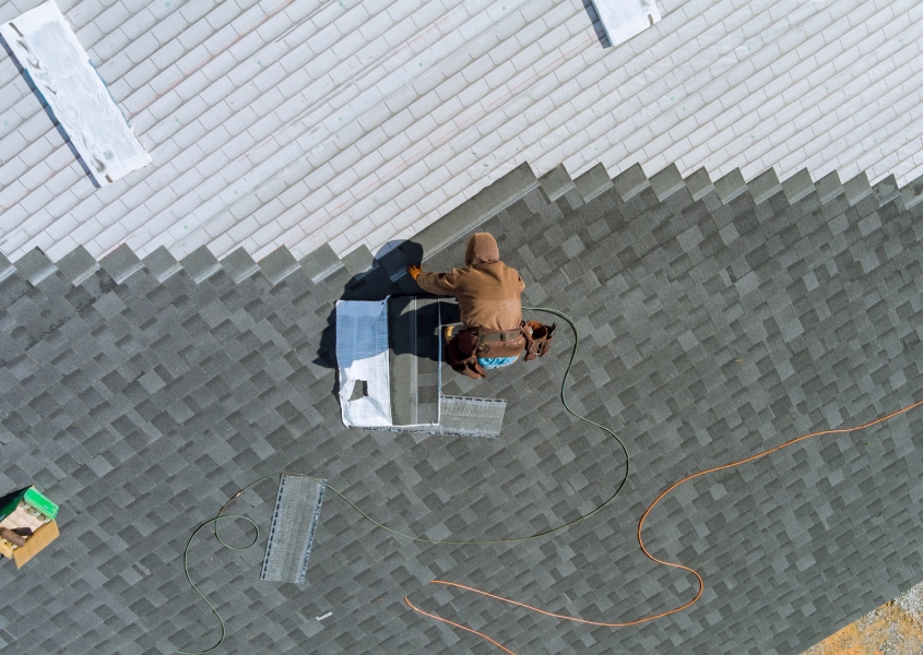 A skilled worker replaces shingles on a roof