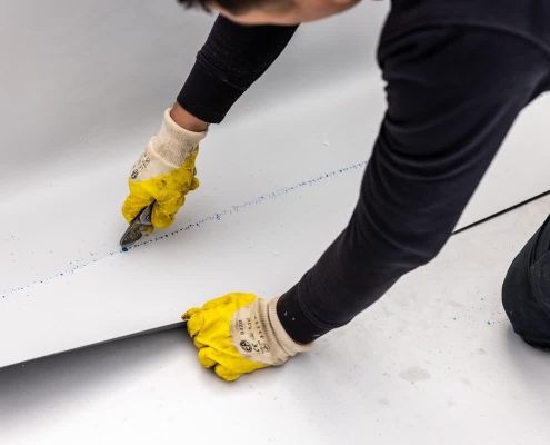 A roofer conducting preventative roof maintenance on a commercial building's flat roof.