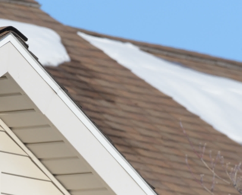Roofer removing snow from residential roof in Wisconsin winter