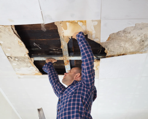 Roofer performing commercial roof leak diagnosis with moisture mapping and infrared detection tools