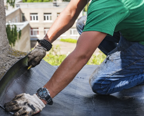 Roofer examining a failed patch to diagnose roof repair failure on a commercial building