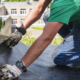 Roofer examining a failed patch to diagnose roof repair failure on a commercial building